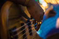 Close-up image of a bass guitar players hands.